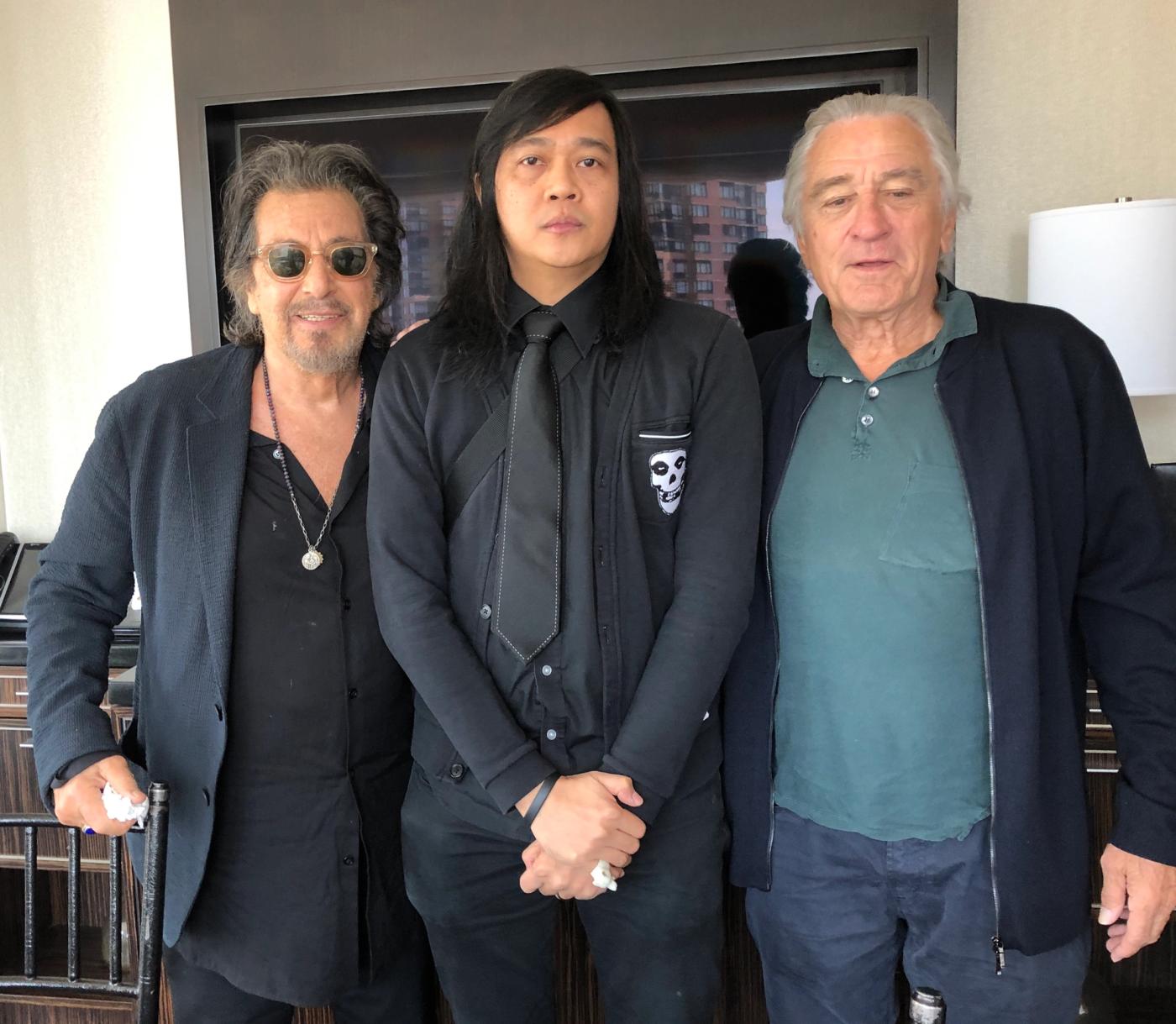 Author Igan D’Bayan in black stands between Al Pacino and Robert De Niro in a New York hotel suite