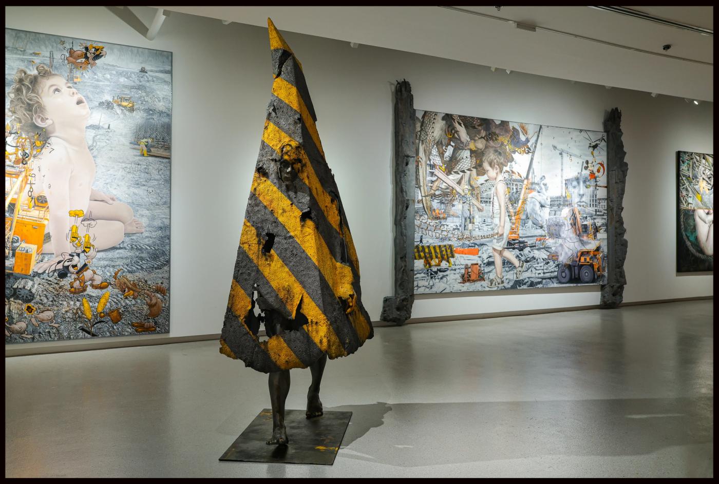 Installation view of Ronald Ventura’s ‘Kalupaan’ at Cloudgrey Gallery: a hazard-striped cone figure between large paintings