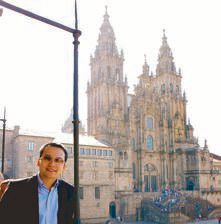 Thai Airways executive Sern Chupikulchai smiling before the towers of the Santiago de Compostela Cathedral