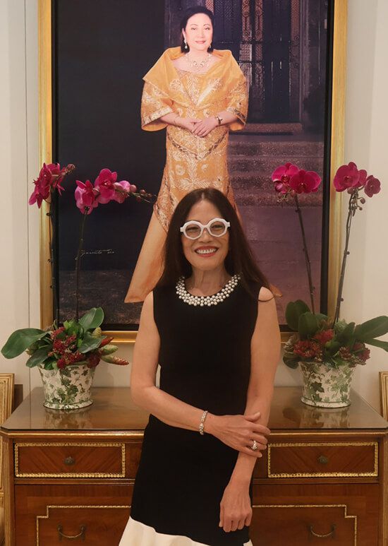 Cecile Licad in black stands before a portrait of Nedy Tantoco in a golden gown, flanked by orchids