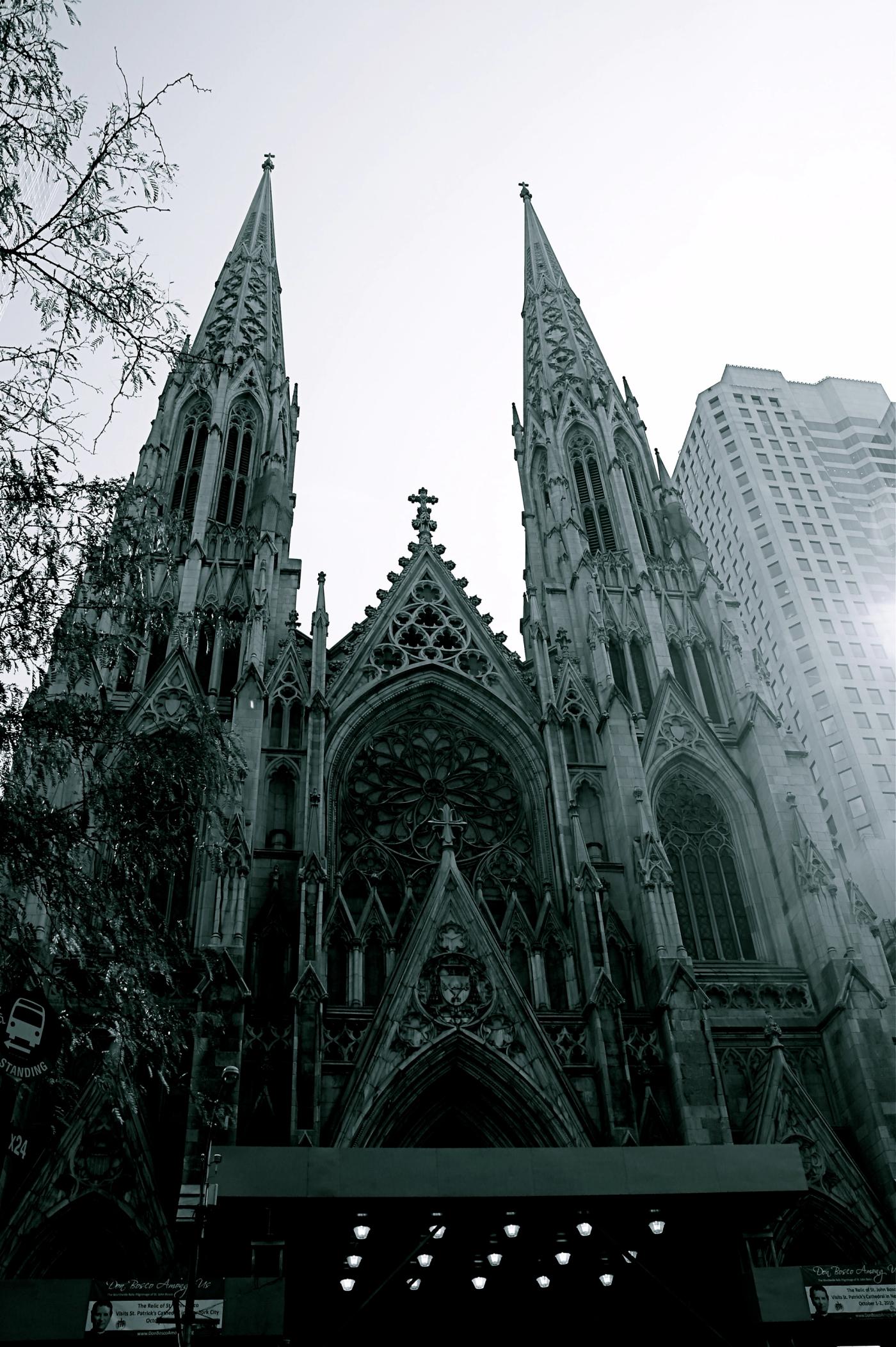 The twin Gothic Revival spires and rose window of St. Patrick’s Cathedral on Fifth Avenue, New York, beside a modern high-rise