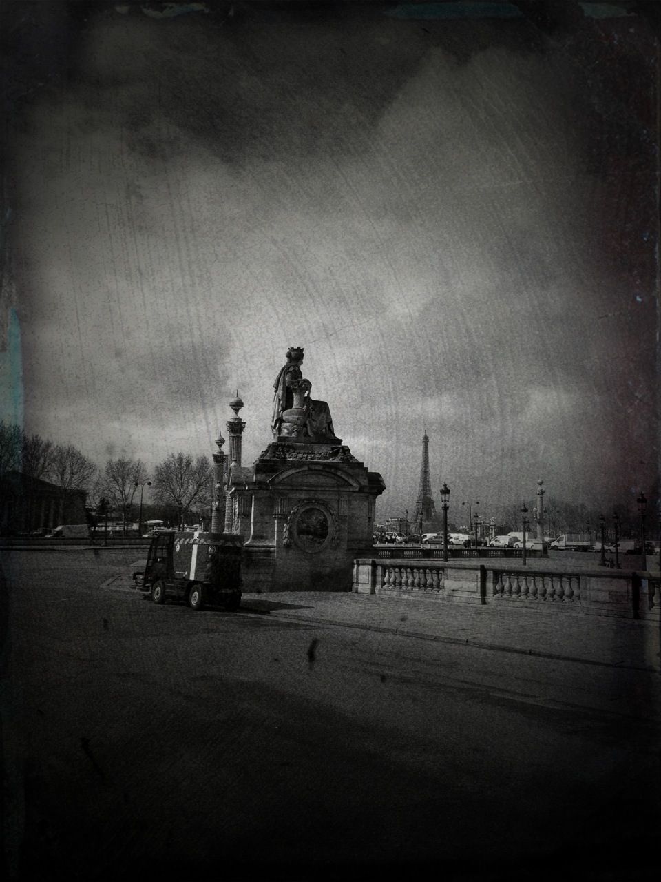 Moody black and white square with a crowned stone statue, the Eiffel Tower hazy on the horizon