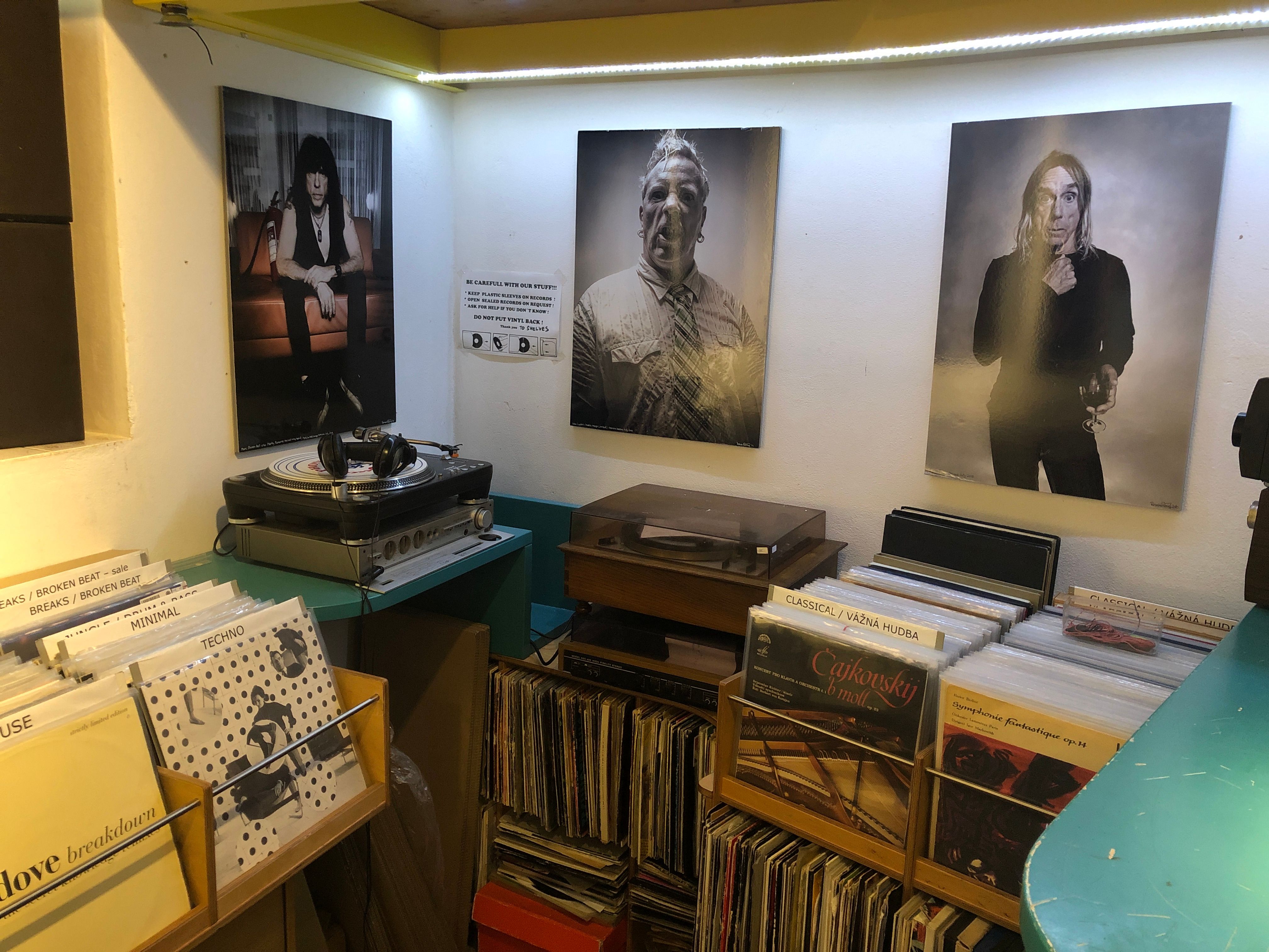 Vintage turntables and crates of LPs beneath three large photo portraits in a record shop corner