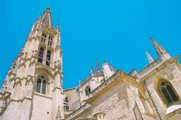 Gothic spires and pinnacles of Burgos Cathedral seen from below against a deep blue sky
