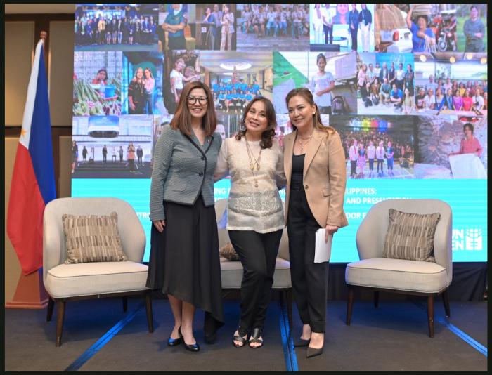 Australian Ambassador HK Yu, Senator Loren Legarda and Karen Davila stand together on the UN Women stage before a collage of program photos, a Philippine flag at left