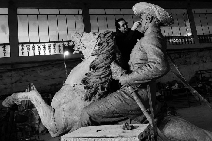 Spanish artist Ginés Serrán works on the face of his full scale clay model of General Martín Delgado on horseback, later cast in bronze for Iloilo, in a studio with tall windows