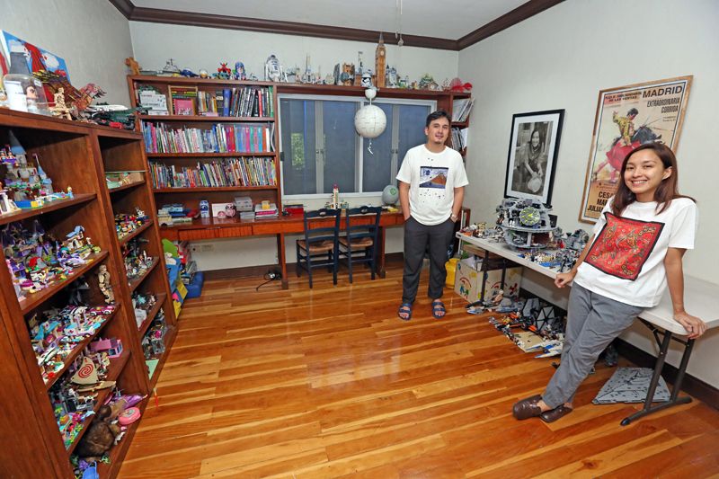 Martin Honasan and Barbie Almalbis stand in a playroom lined with Lego, books, Star Wars models and a Madrid bullfight poster