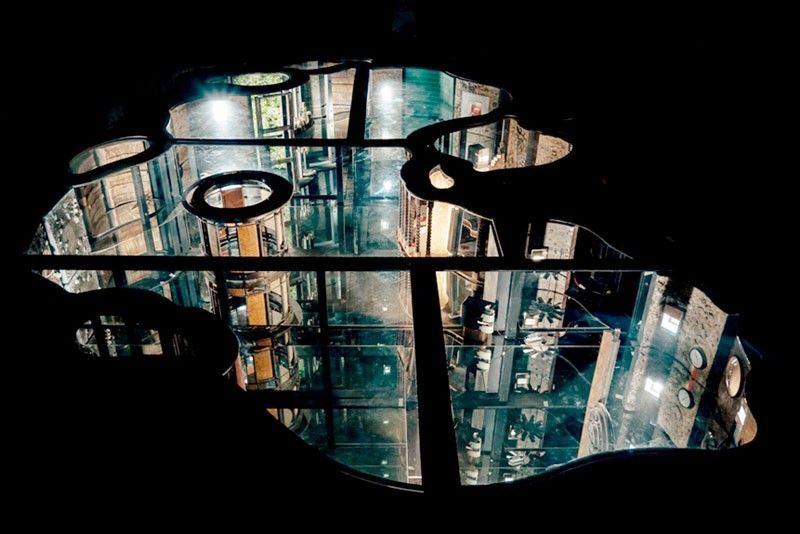 Top-down view of Mark Justiniani’s glass and steel installation Island Weather, featuring lighted infinite mirrors and geometric structural shapes resembling islands