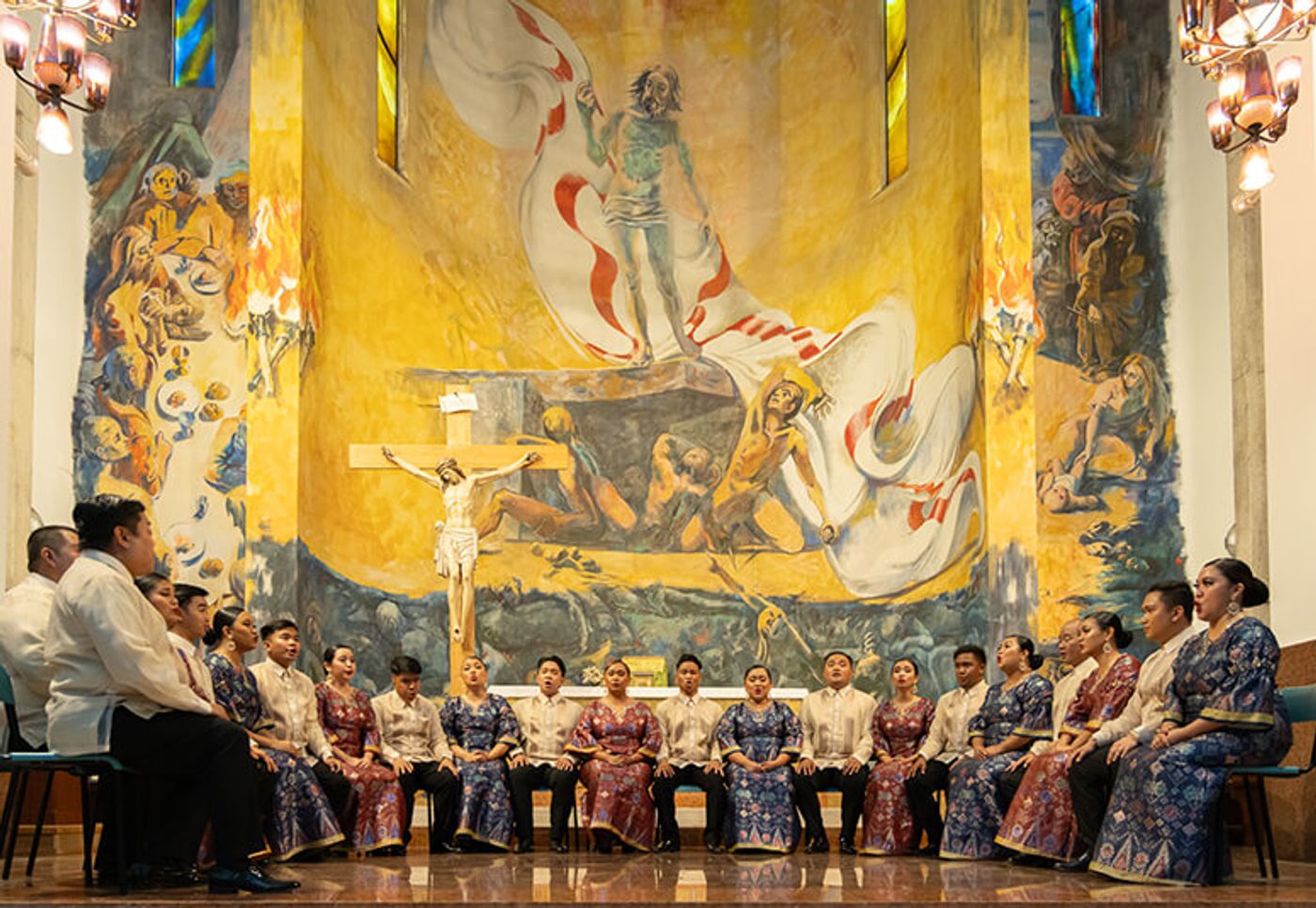 The Philippine Madrigal Singers seated in formal wear beneath a vast church mural in Mestre