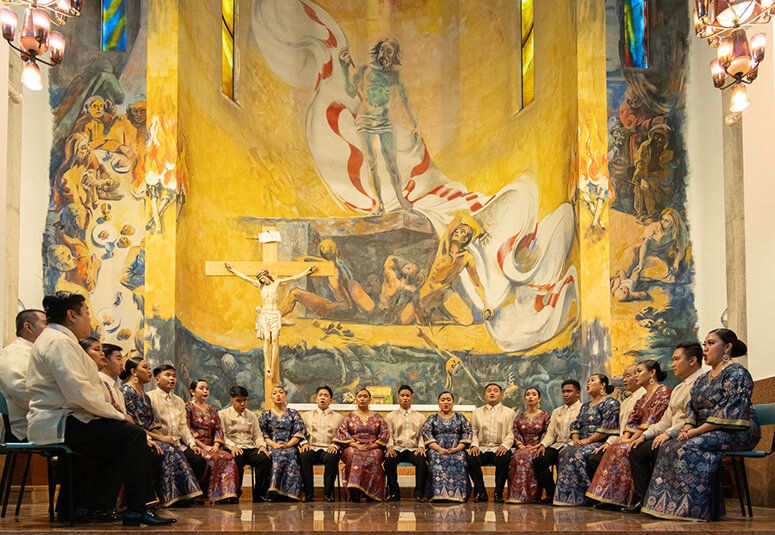 The Philippine Madrigal Singers seated in formal wear beneath a vast church mural in Mestre