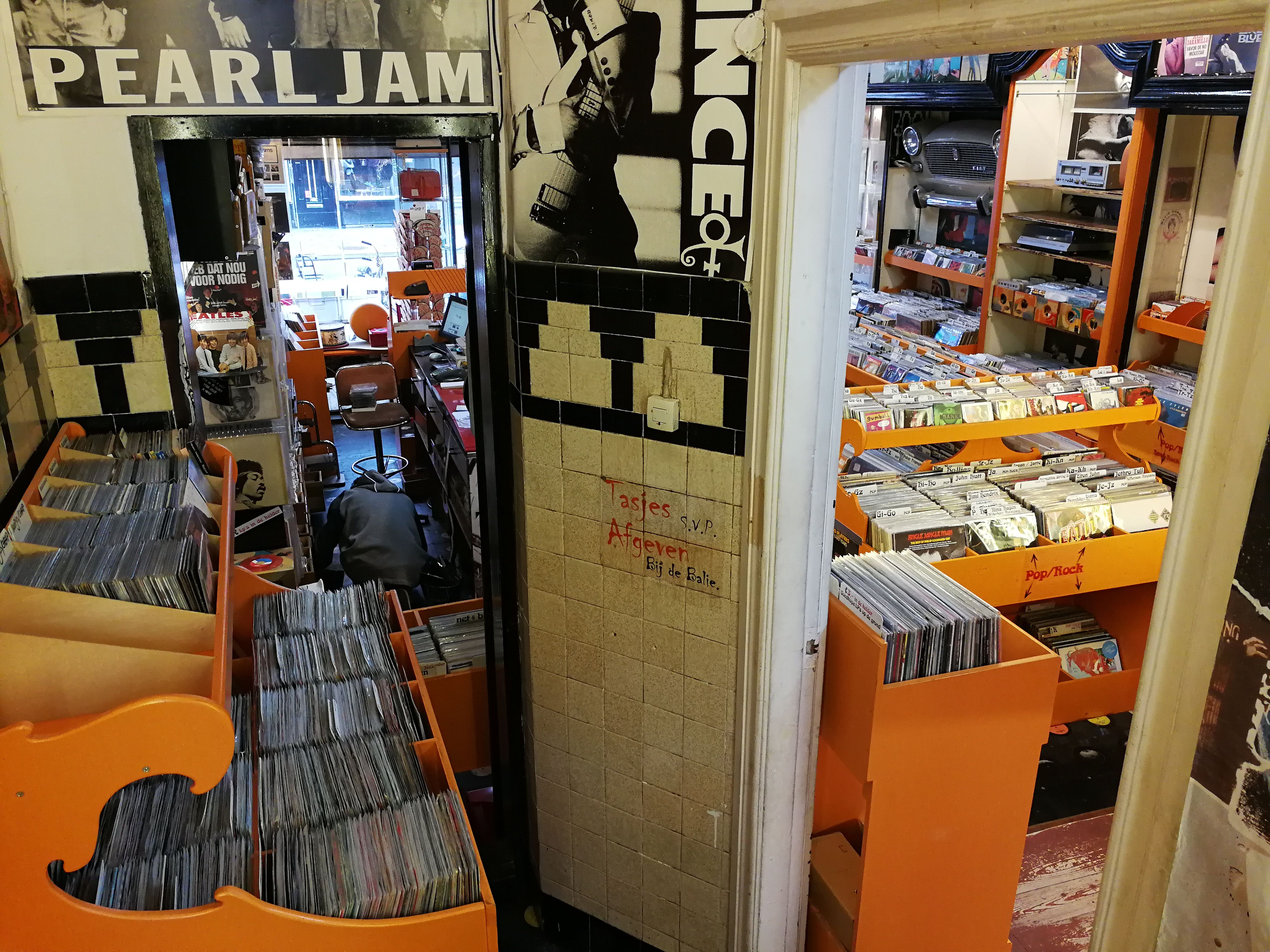 Orange-tiled record shop crammed with vinyl crates beneath Pearl Jam and Prince posters