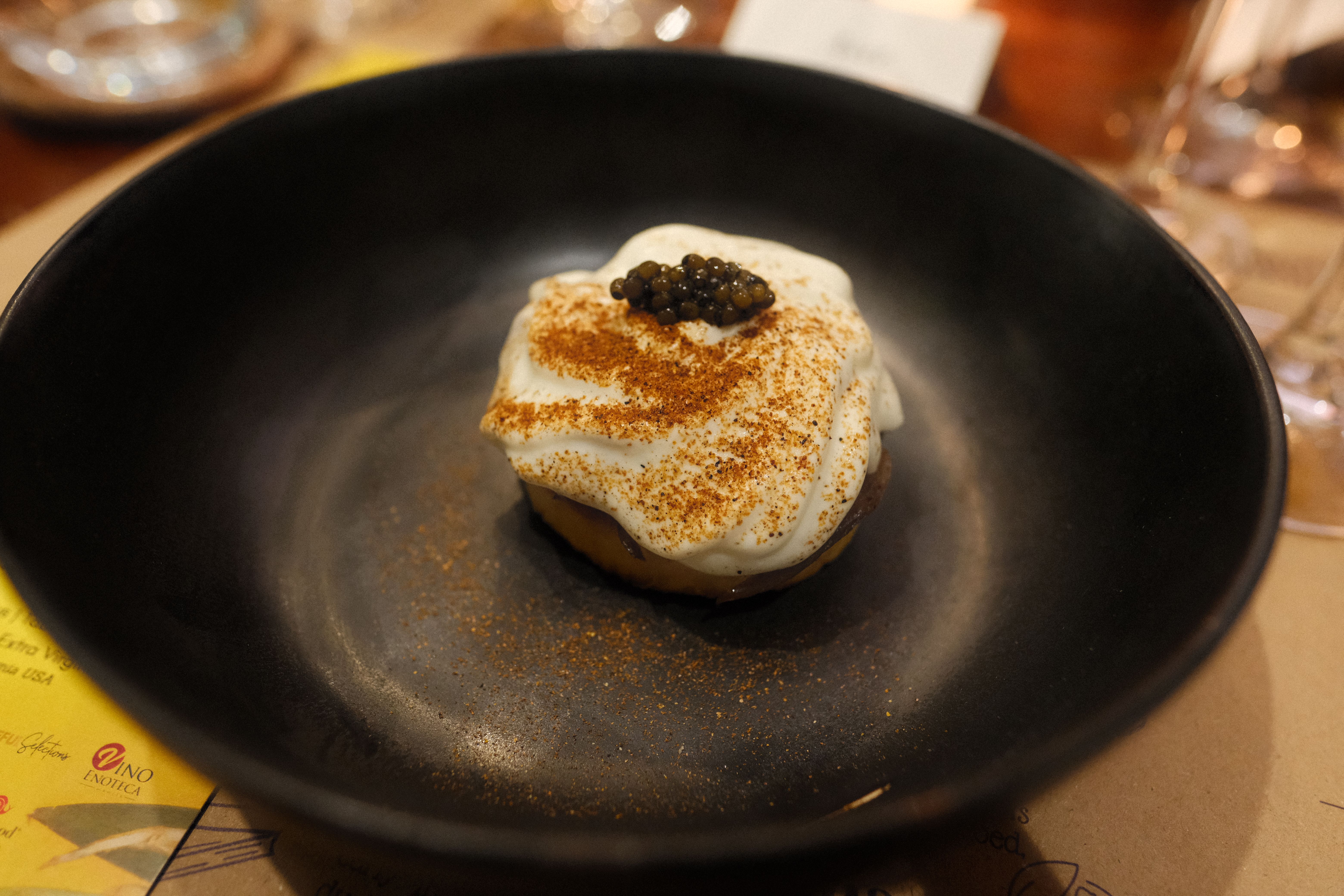 Whipped kesong puti crowned with caviar and dusted with toasted pandesal crumbs in a black bowl at The Fatted Calf