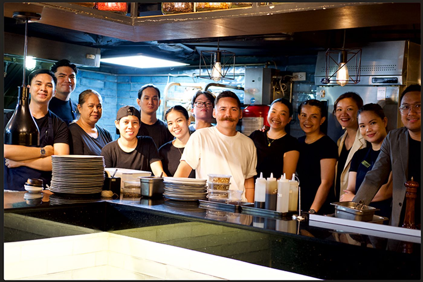 The Savage team, chef Josh Boutwood at center in white, pose together behind the kitchen counter