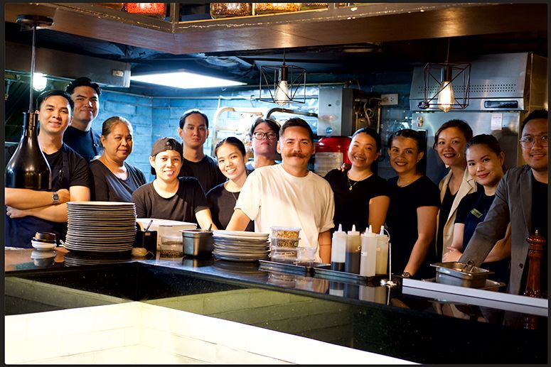 The Savage team, chef Josh Boutwood at center in white, pose together behind the kitchen counter
