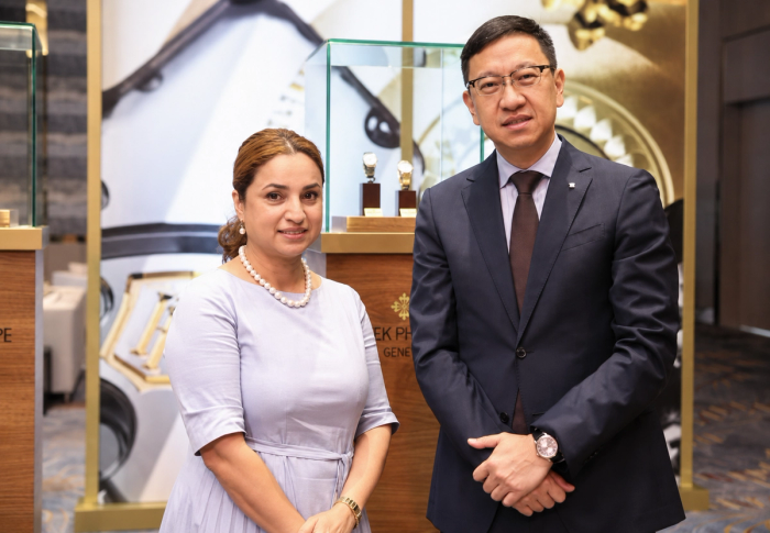 Deepa Chatrath and Emerson Yao stand beside a gilded Patek Philippe display at the launch