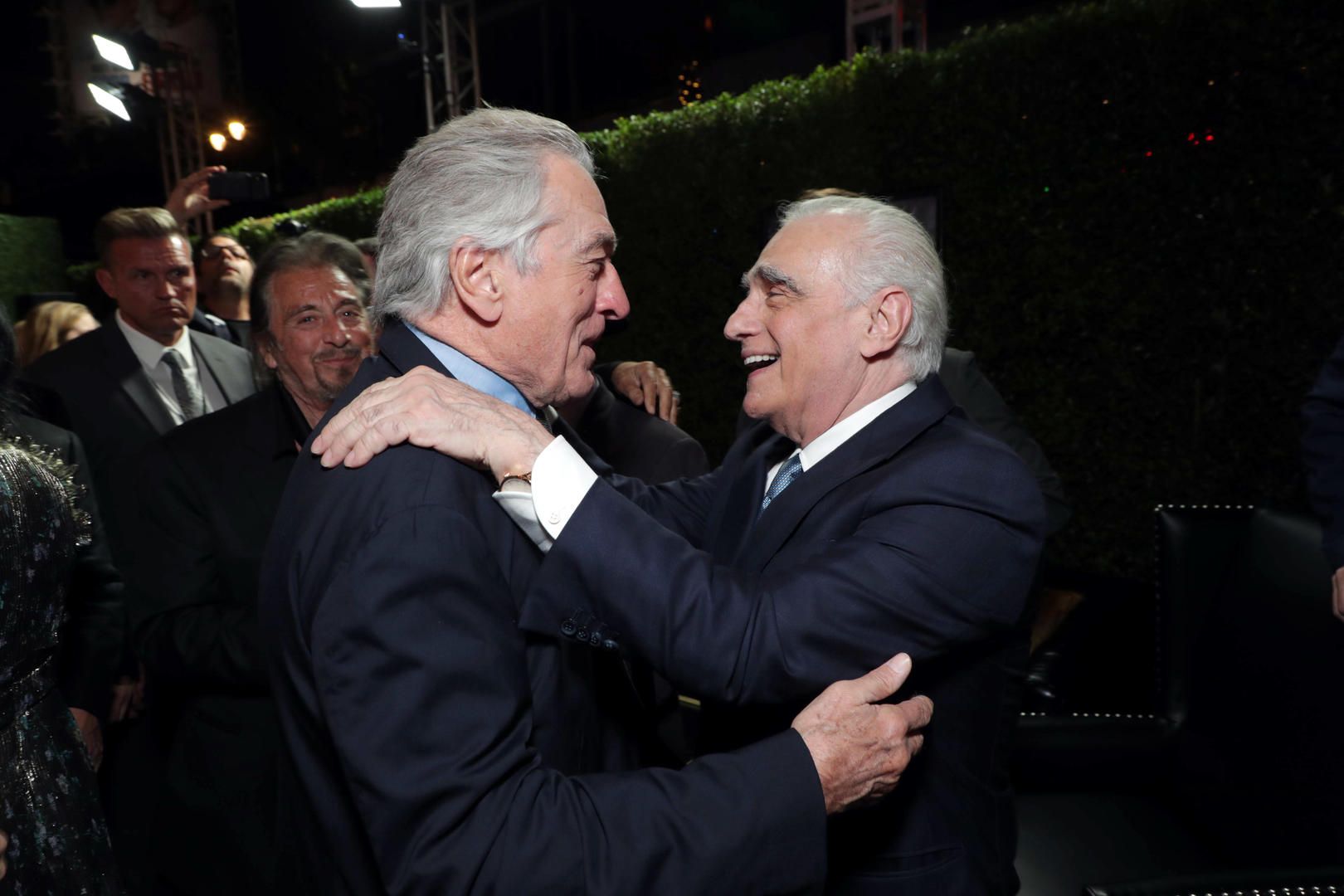 Robert De Niro and Martin Scorsese greet each other warmly amid the premiere crowd at night