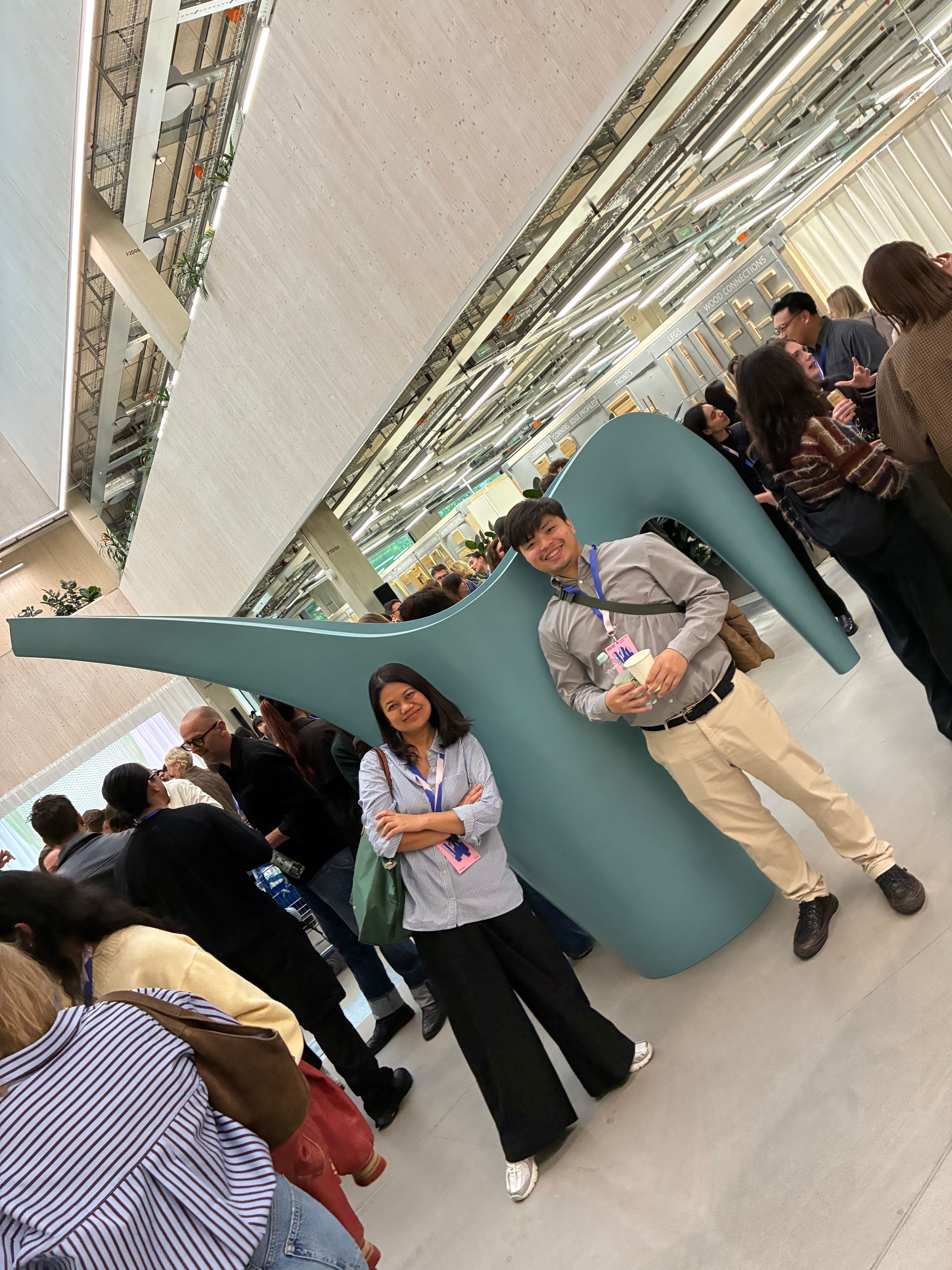 Attendees pose with a giant teal watering can sculpture in the bright IKEA of Sweden atrium during Democratic Design Days