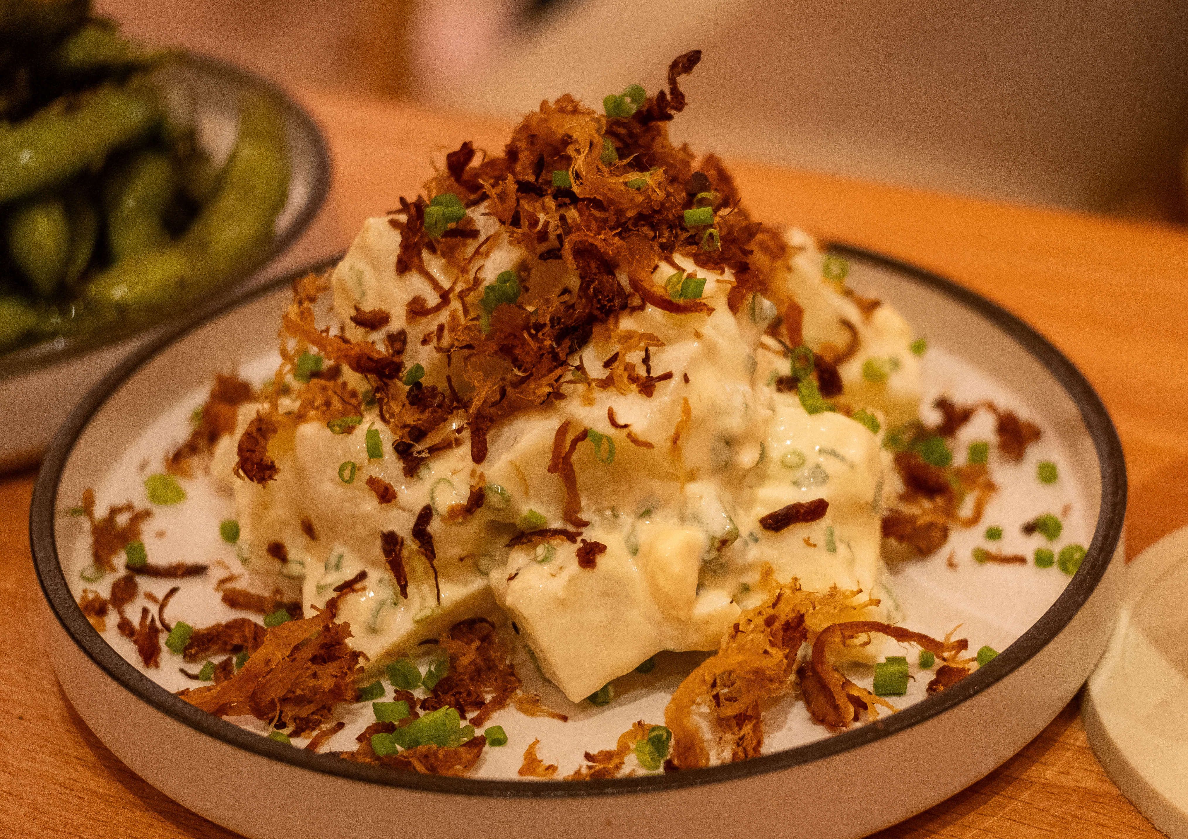 Ippudo’s potato chashu salad, creamy potato chunks piled with crispy fried chashu shreds and scallions, edamame alongside