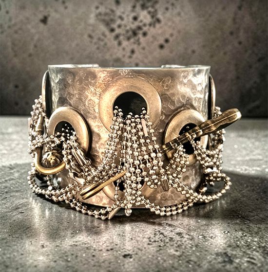 Oxidized silver cuff by Michelline Syjuco draped with strands of miniature ball chain threaded through grommets