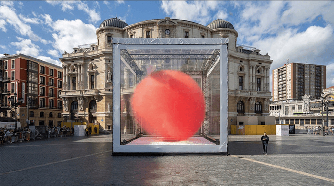 A ten-meter red globe tilted inside a scaffolding cube on the plaza of Teatro Arriaga, Bilbao