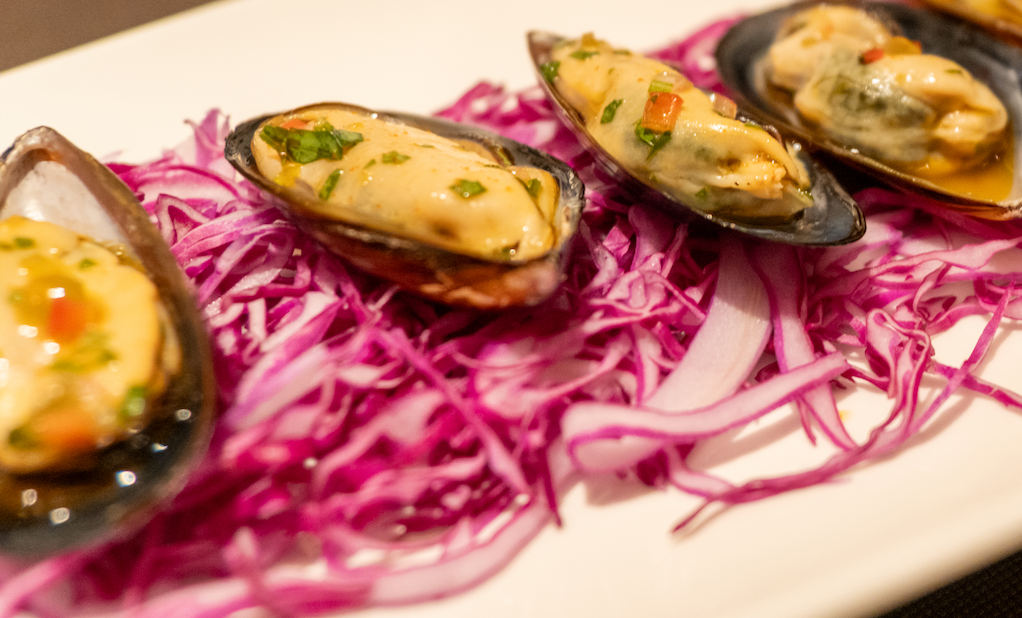 Baked mussels on the half shell topped with creamy chili-herb sauce, on a bed of shredded purple cabbage