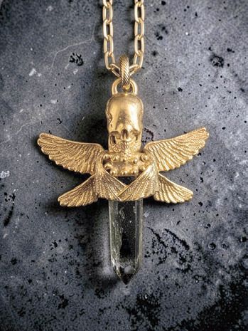 Gold pendant by Michelline Syjuco of a skull with spread wings welded above a rutilated quartz point