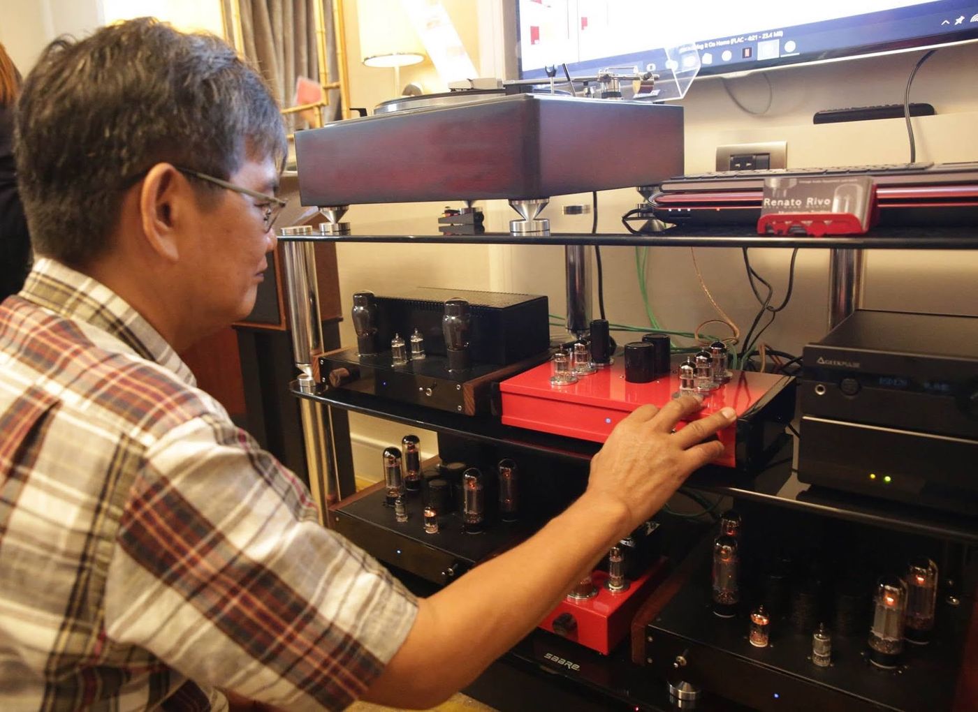 Rene Rivo reaches for a red tube amplifier on a rack of turntables and valve gear at the Hi-Fi Show in Dusit Thani Hotel