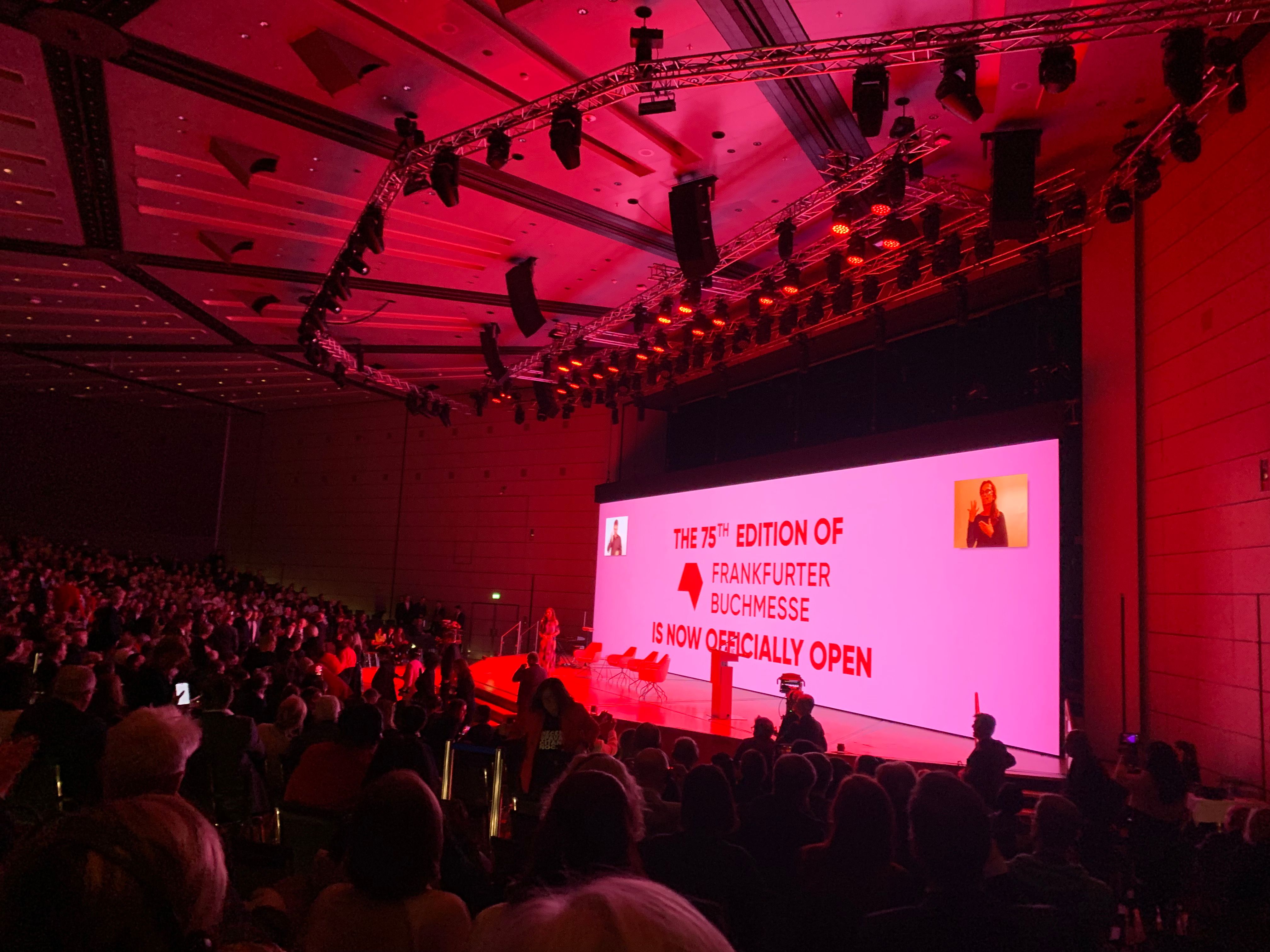 A packed auditorium bathed in red light at the opening ceremony of the 75th Frankfurter Buchmesse