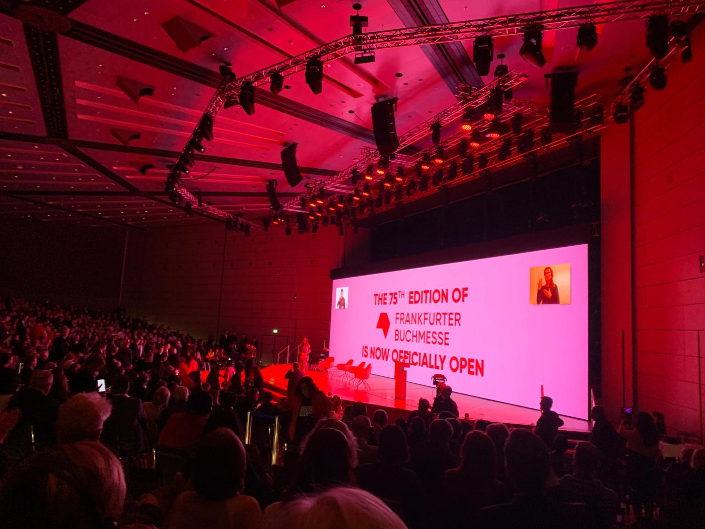 A packed auditorium bathed in red light at the opening ceremony of the 75th Frankfurter Buchmesse