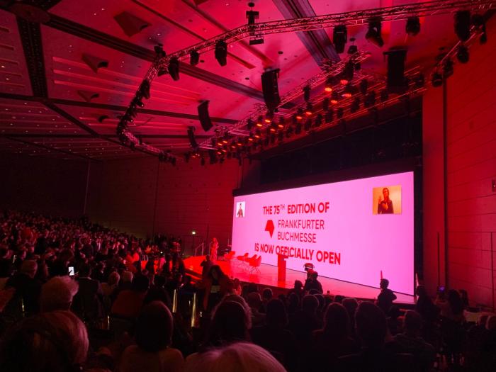 A packed auditorium bathed in red light at the opening ceremony of the 75th Frankfurter Buchmesse