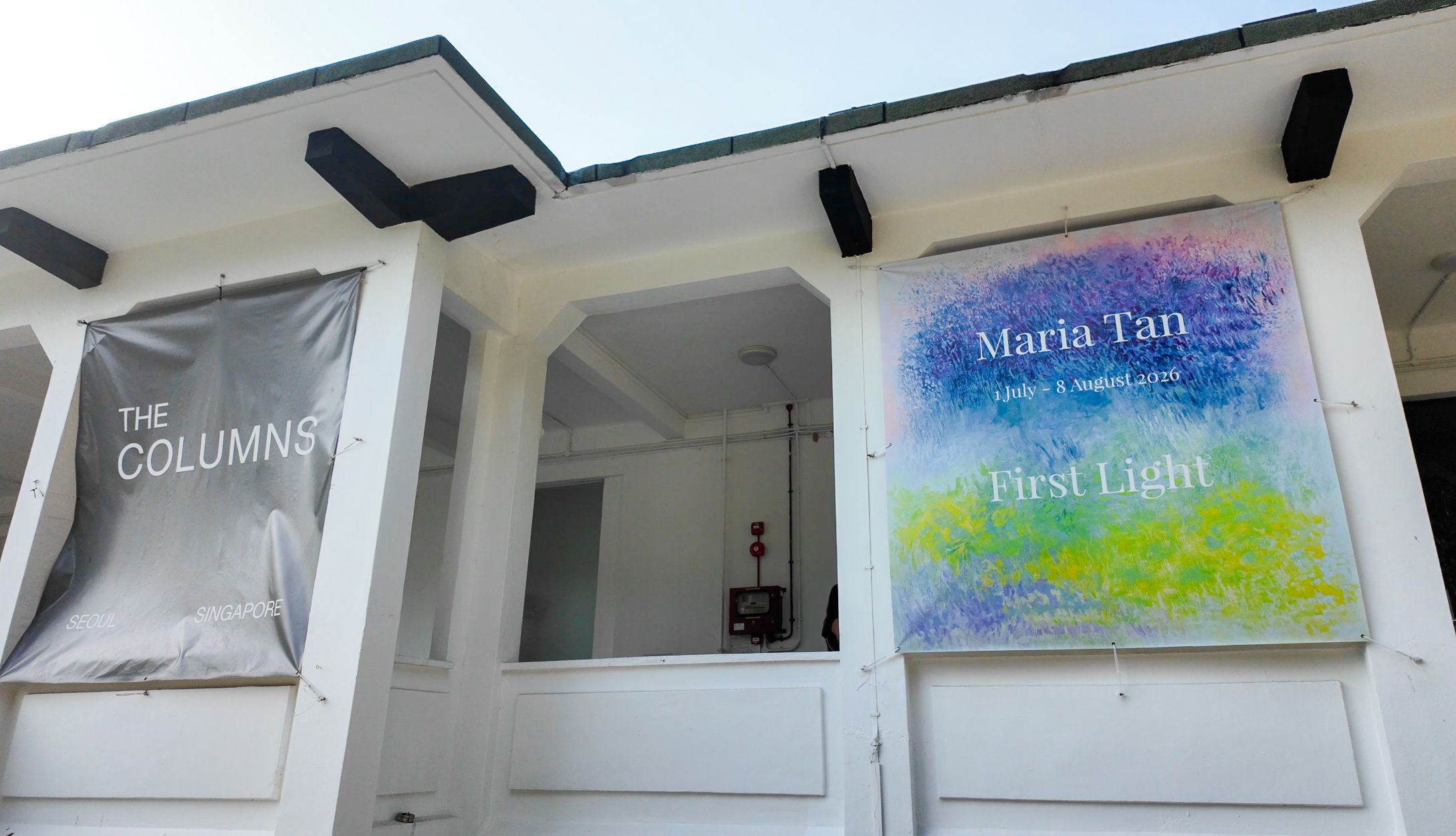 Exhibition banners for Maria Tan’s First Light on the white facade of The Columns Gallery in Gillman Barracks, Singapore