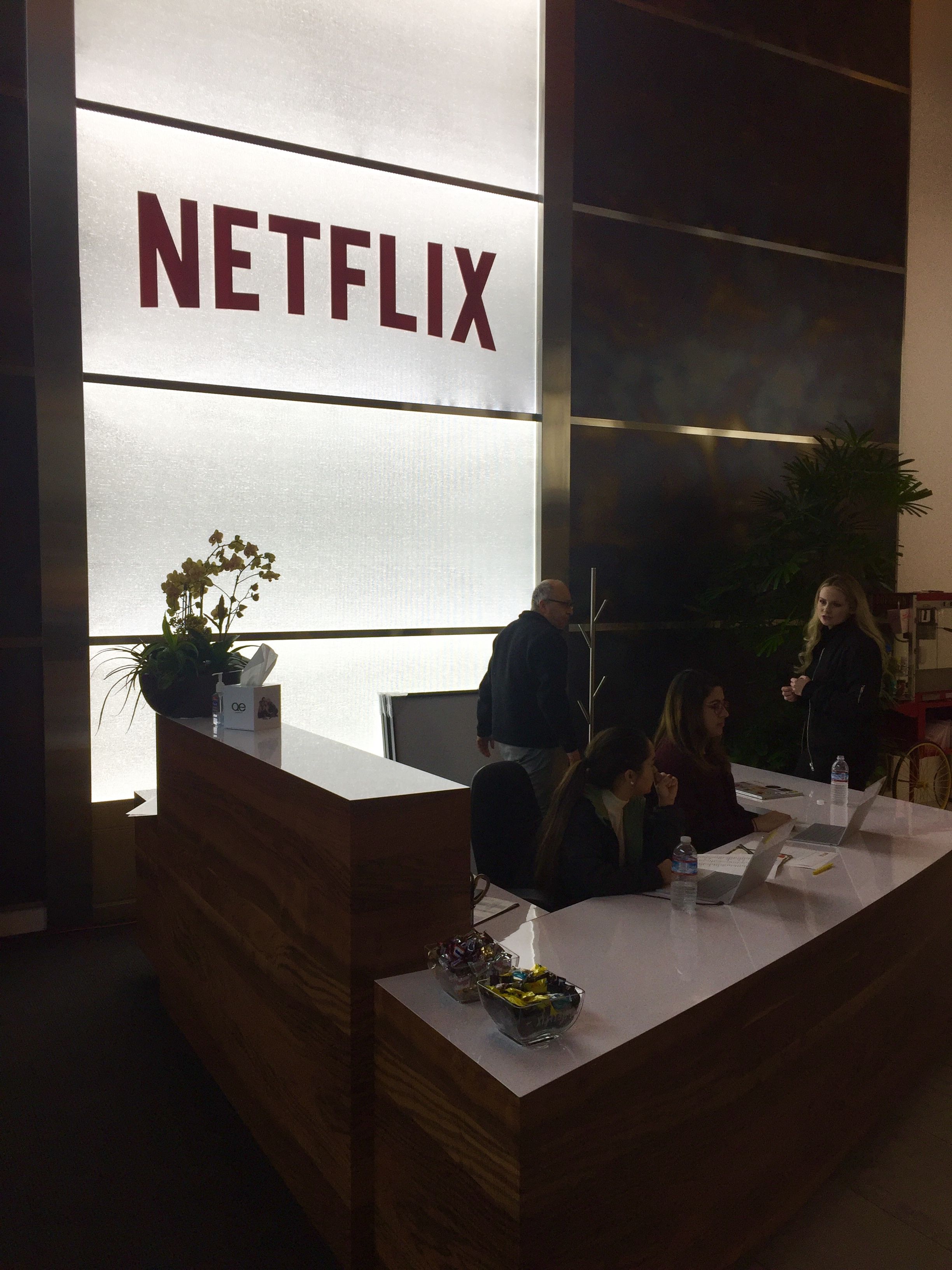 Reception desk beneath a glowing Netflix sign in the company’s Los Gatos lobby