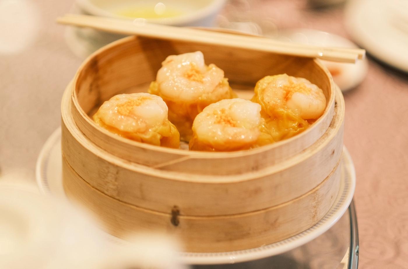 Four steamed pork and shrimp siomai in a bamboo steamer with chopsticks at Summer Palace, Edsa Shangri-La