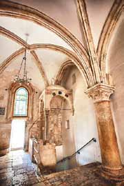 Stone arches, a stained glass window and vaulted ceiling in the Hall of the Last Supper