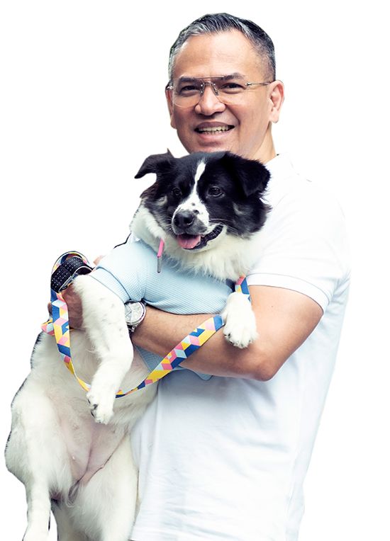 Jean Paul Manuud, in a white polo and glasses, cradles Bistro, the black-and-white rescued dog, in his arms