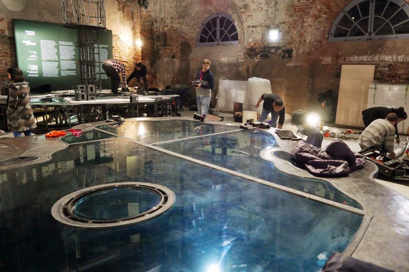 Crew dismantling Mark Justiniani’s Island Weather inside the Arsenale, its mirrored glass islands still reflecting the brick vaults