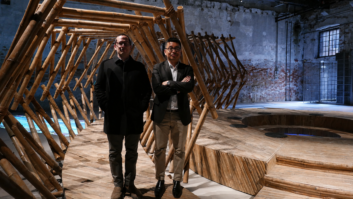 Speakers Anthony Medrano and Mike Pante stand on the wooden deck of the bamboo Tripa de Gallina installation at the Philippine Pavilion in Venice