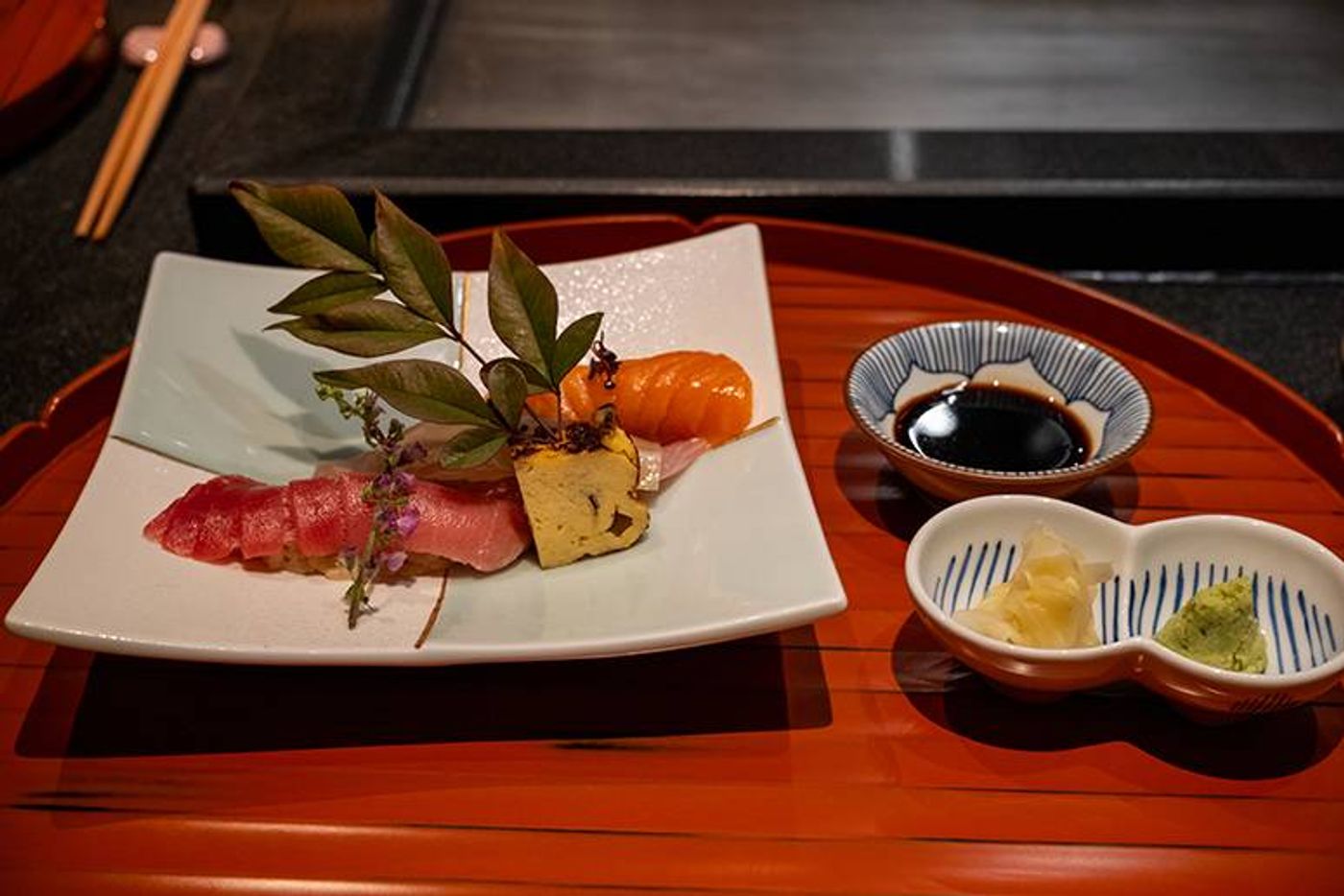 Seasonal sushi plate with chutoro, shima-aji and salmon beside soy sauce and pickled garnishes