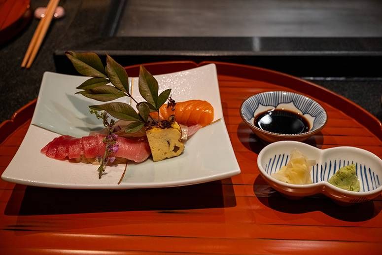 Seasonal sushi plate with chutoro, shima-aji and salmon beside soy sauce and pickled garnishes