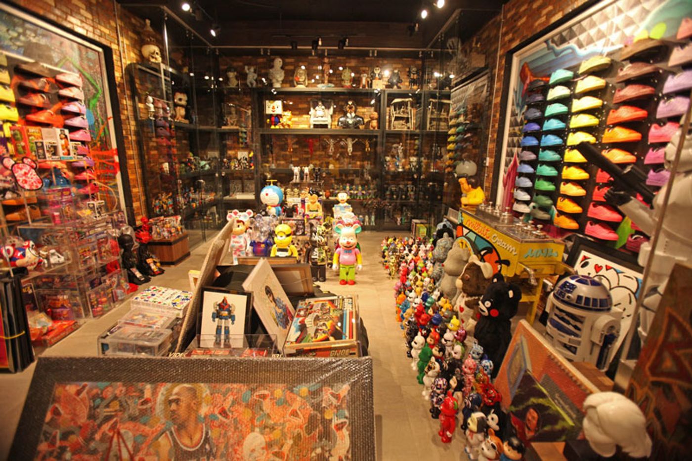 A room lined floor to ceiling with designer toys, Bearbricks, sneakers on rainbow-ordered shelves, framed art and an R2-D2 unit