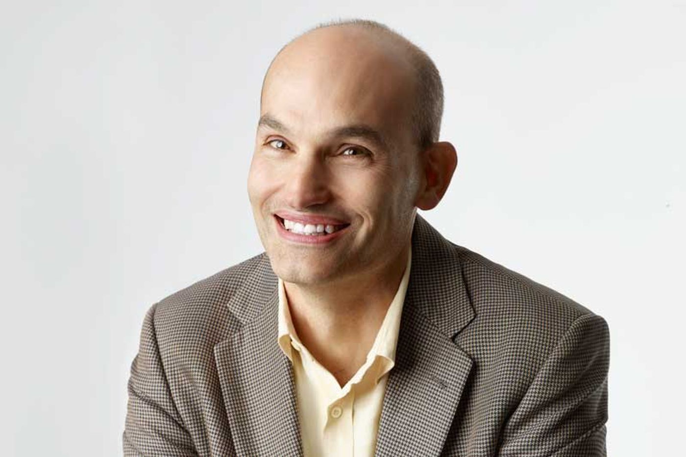 Netflix product VP Todd Yellin smiling in a brown checked blazer against a white studio background