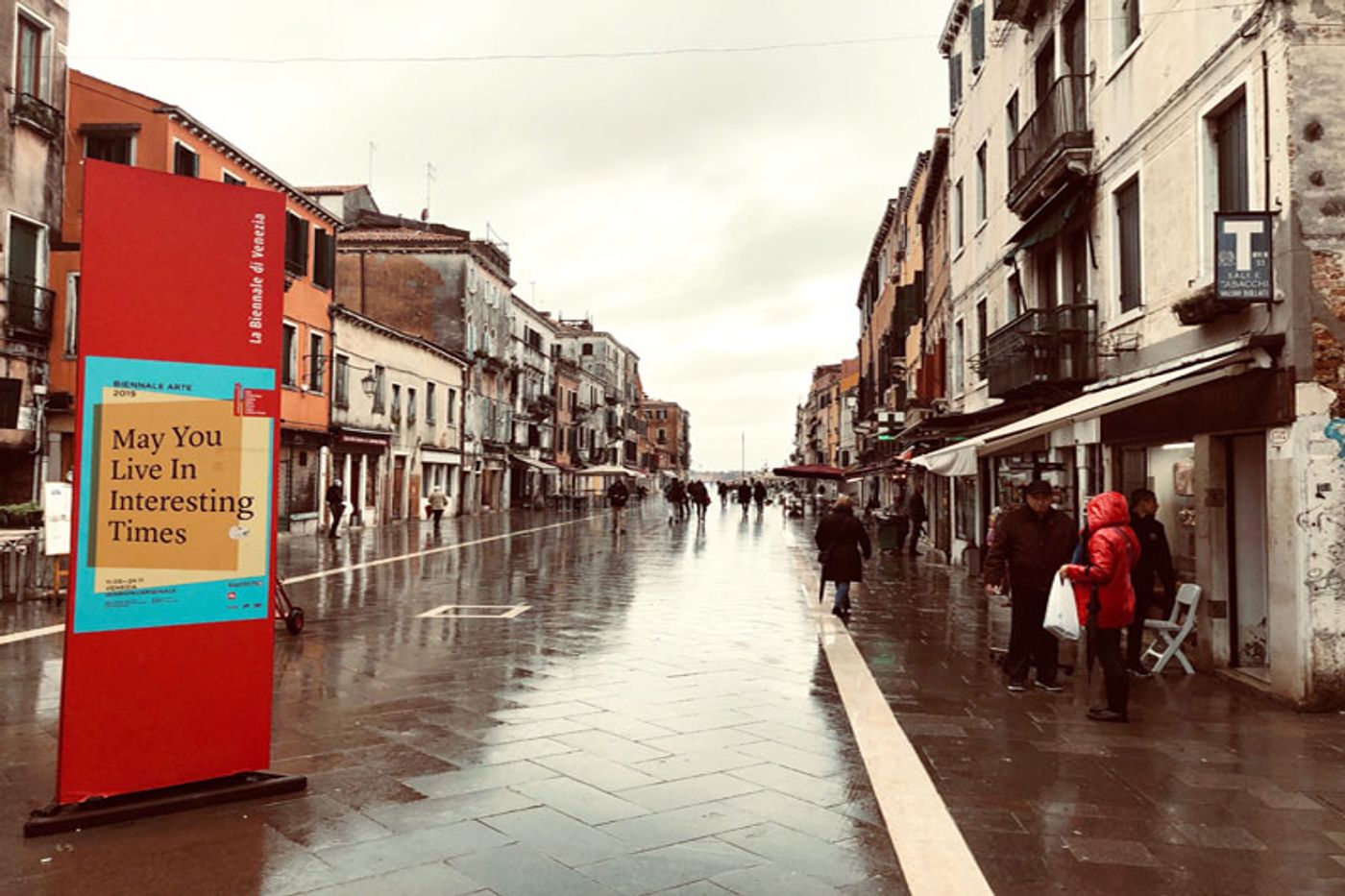Biennale Arte 2019 banner reading May You Live In Interesting Times on a wet Venice street