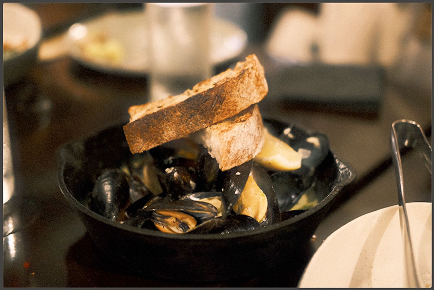 A cast-iron pan of Chilean mussels topped with two slices of toasted sourdough