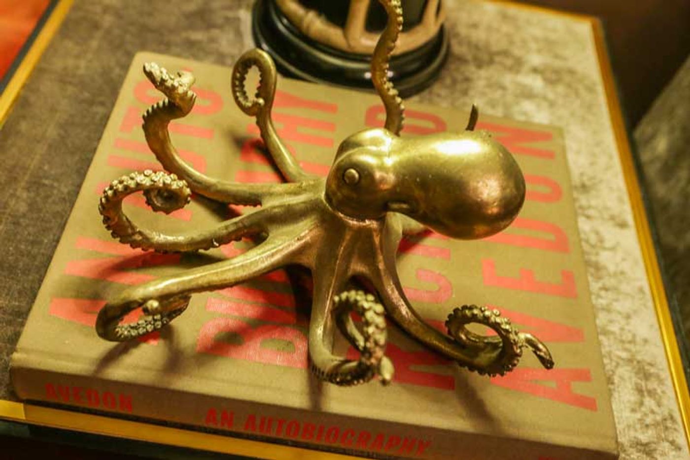 A brass octopus sculpture with curling tentacles rests atop a Richard Avedon photography book