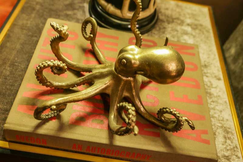 A brass octopus sculpture with curling tentacles rests atop a Richard Avedon photography book