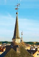 Slender church spire rising over the rooftops of Alcalá de Henares, a stork nest clinging near its weathervane