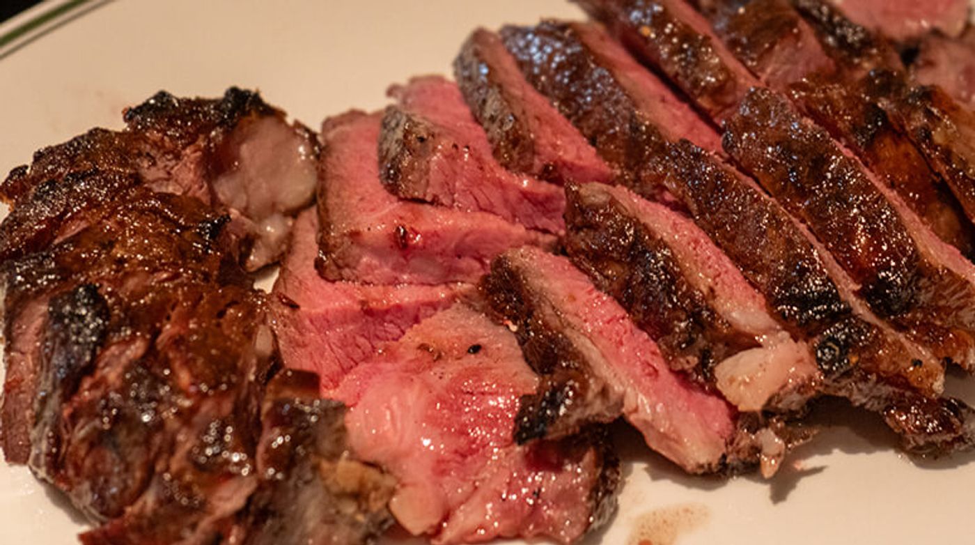 Closeup of thick sliced USDA Prime steak, its seared crust giving way to a rosy pink center