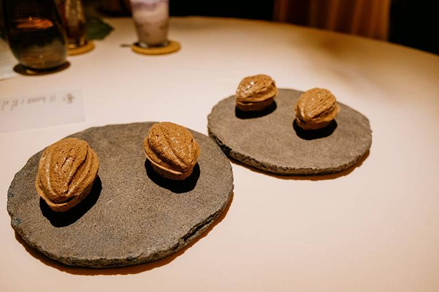 Walnut-shaped meringue shells filled with sorbet and ganache, resting on rough stone discs