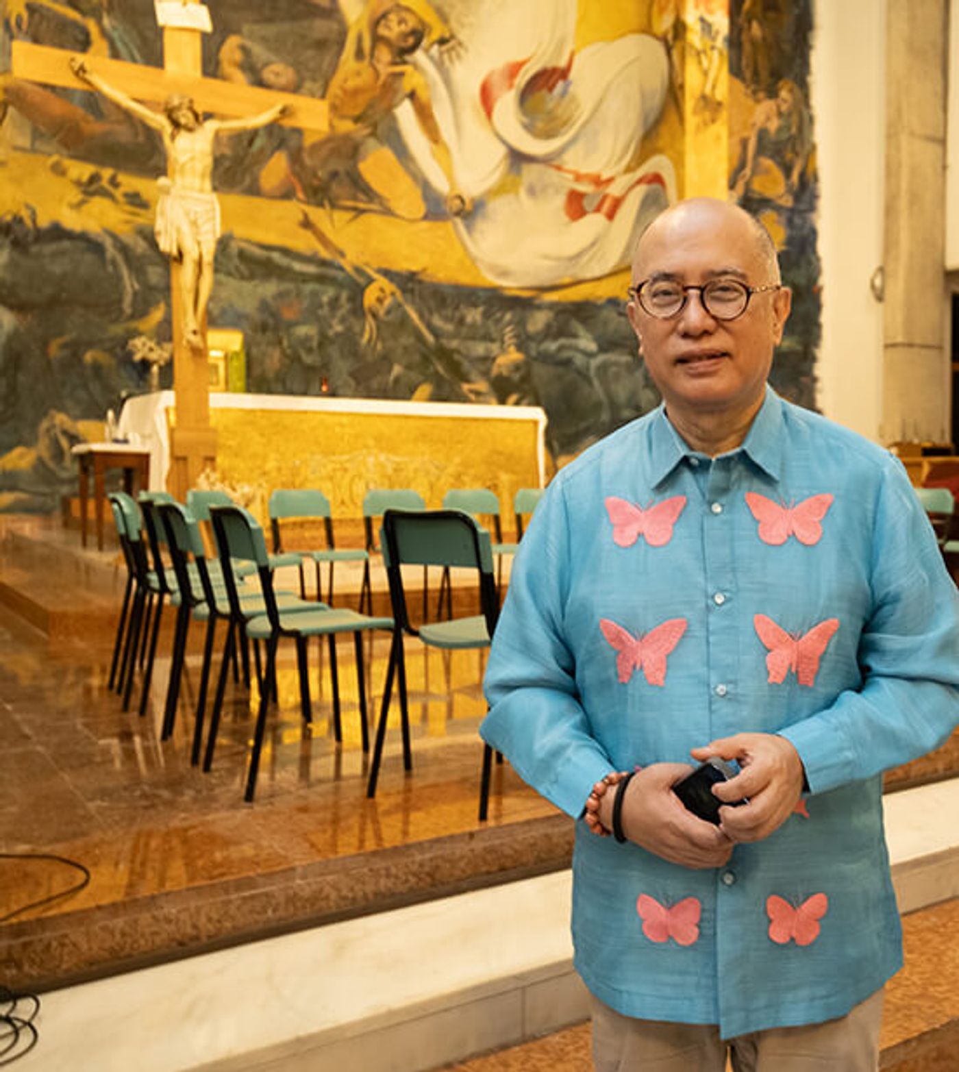 NCCA chair Victorino Mapa Manalo in a blue butterfly-appliqued shirt inside a muraled church