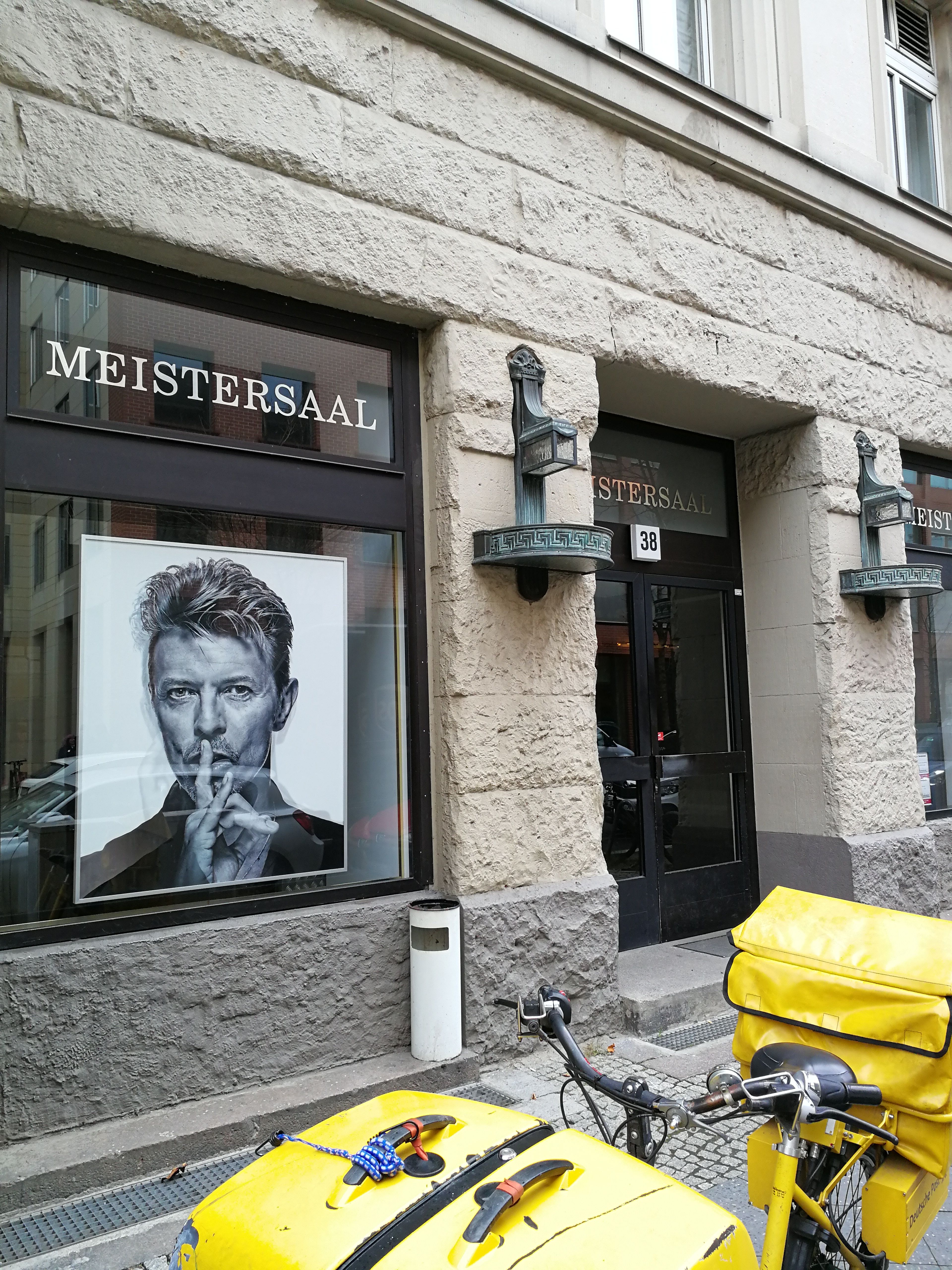 David Bowie portrait in the window of Berlin’s Meistersaal, a yellow bicycle parked outside